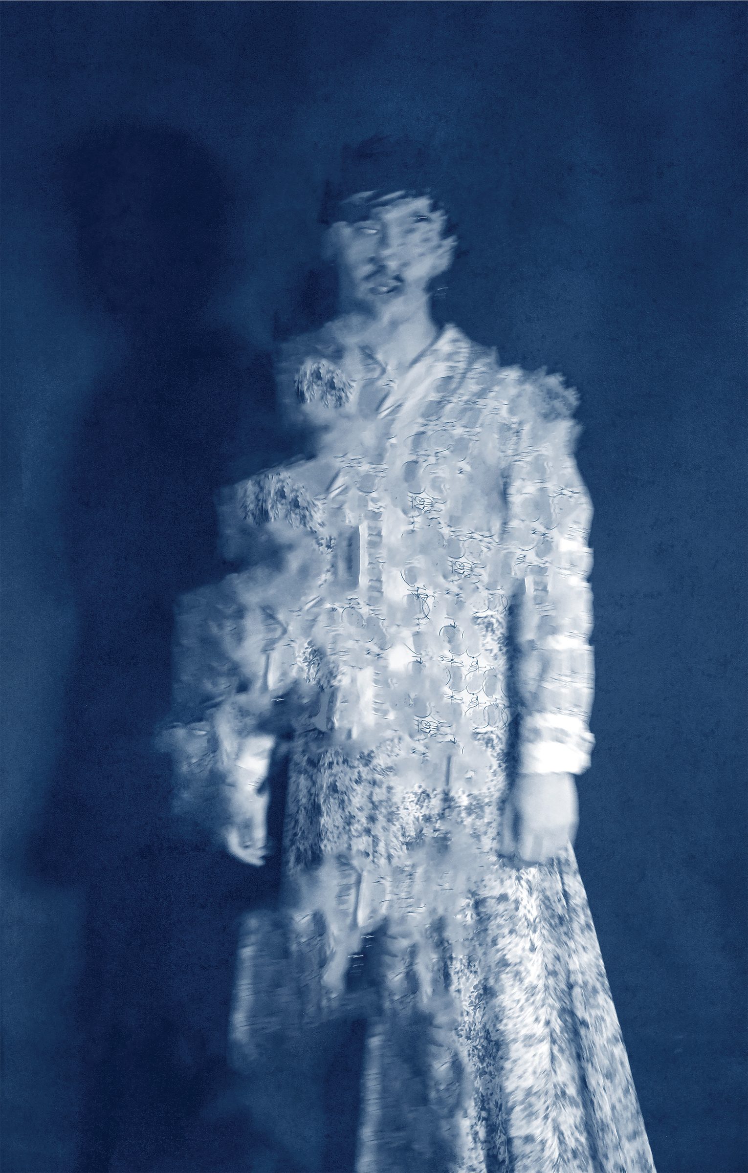 A figure in a long floral garment, face and body blurred into fragments, washed in deep blue.
