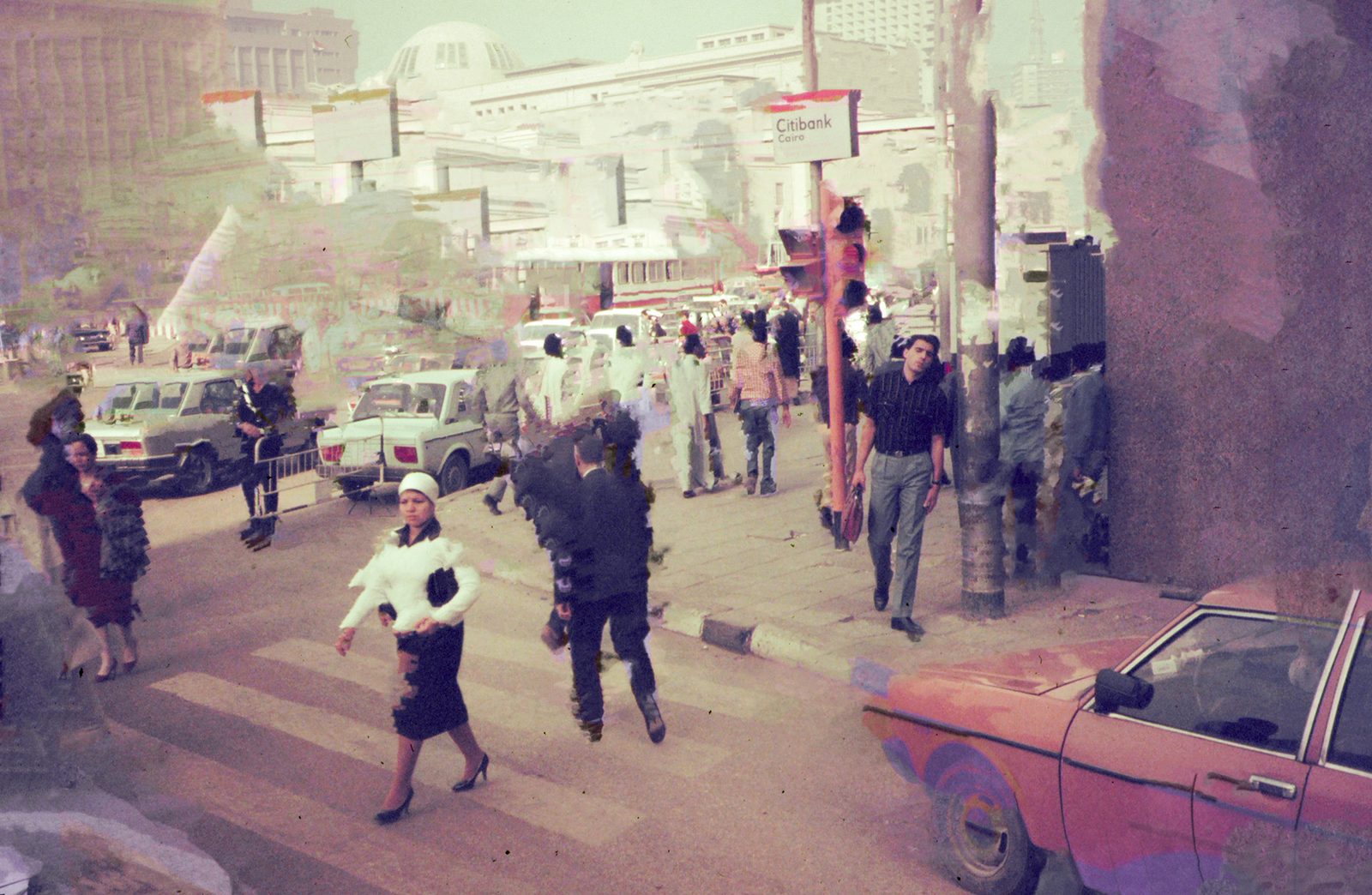 Busy city crosswalk in faded warm tones, pedestrians and old taxis under a domed skyline, torn by patches of digital smear.
